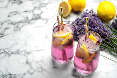 Fresh delicious lemonade with lavender and straws on white marble table. Space for text
