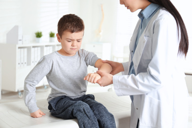 Photo of Professional orthopedist examining little patient's arm  in clinic