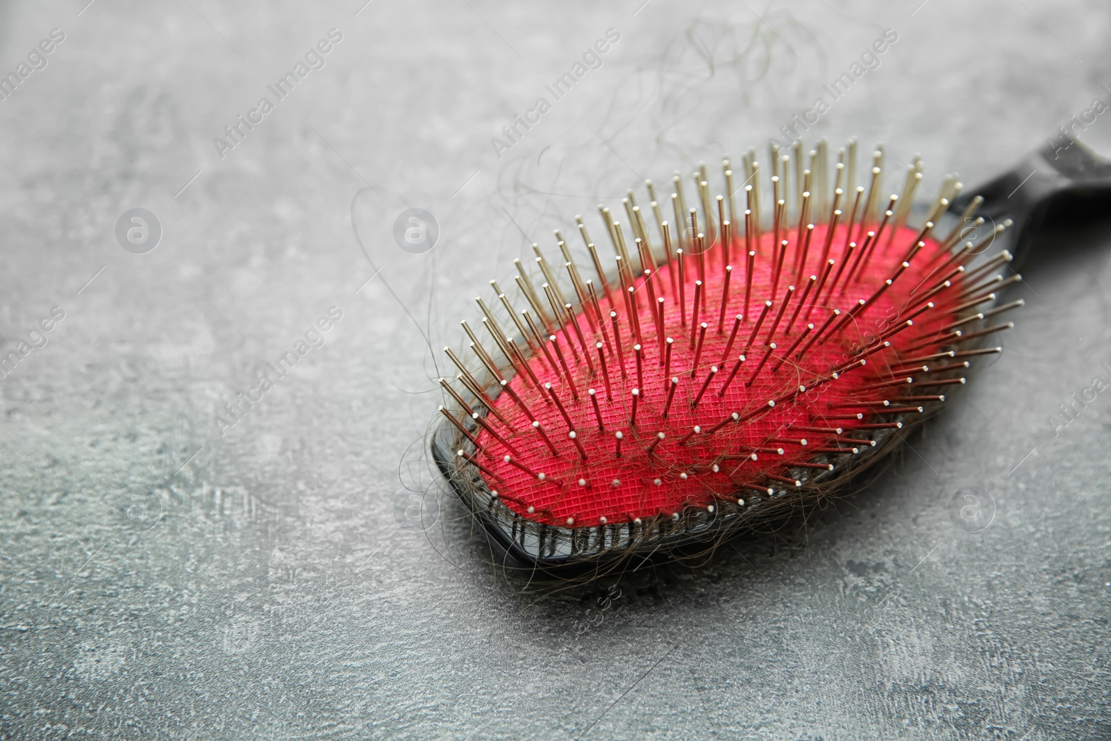 Photo of Brush with lost hair on gray table. Alopecia problem