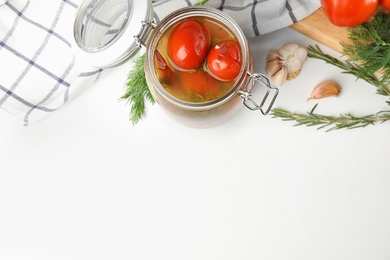 Flat lay composition with pickled tomatoes in glass jar on white table