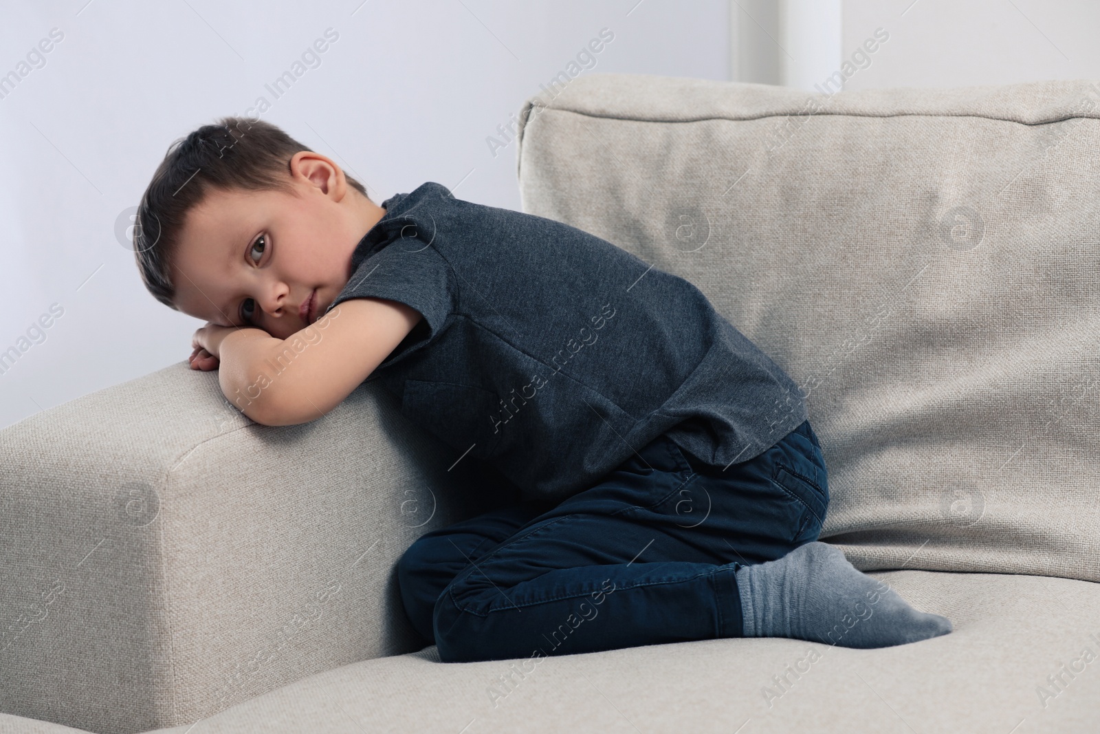 Photo of Sad little boy on sofa at home