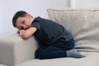 Photo of Sad little boy on sofa at home