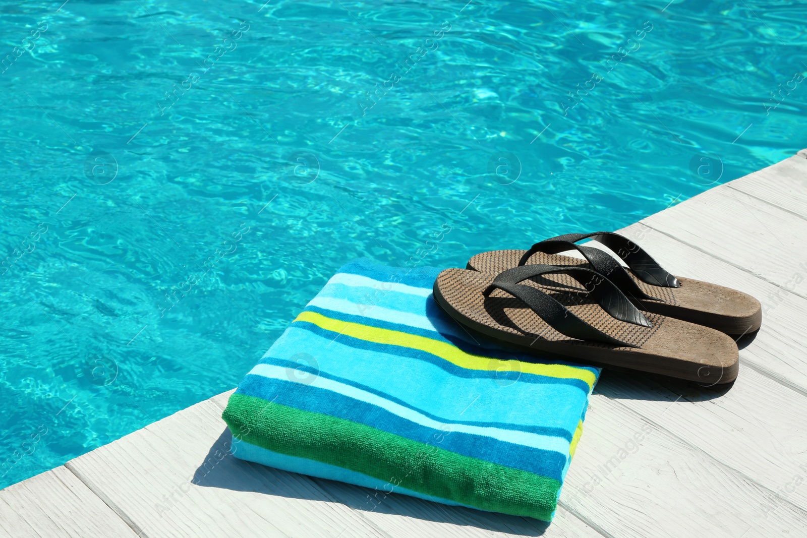 Photo of Beach accessories on wooden deck near swimming pool. Space for text