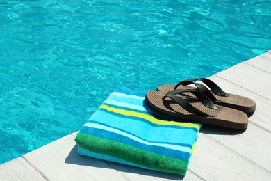 Photo of Beach accessories on wooden deck near swimming pool. Space for text