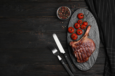 Photo of Delicious beef steak served on black wooden table, flat lay. Space for text