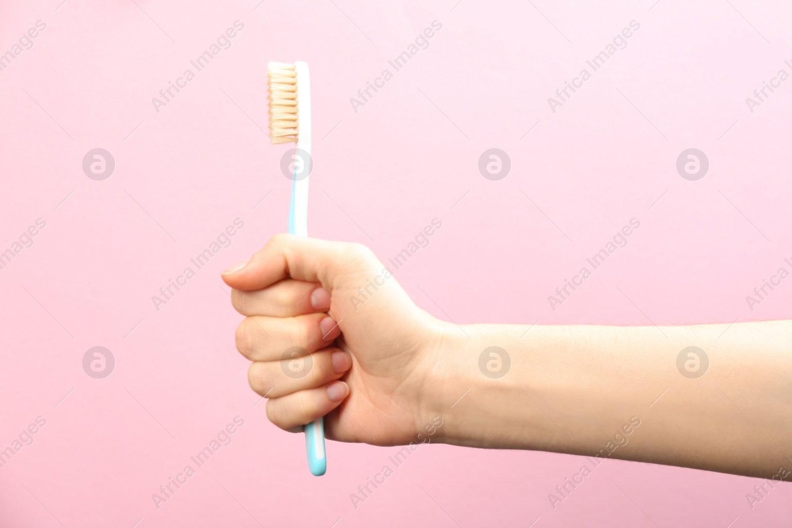 Photo of Woman holding toothbrush with natural bristles on pink background, closeup