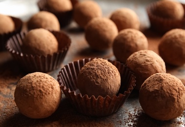 Tasty chocolate truffles powdered with cocoa on grey background