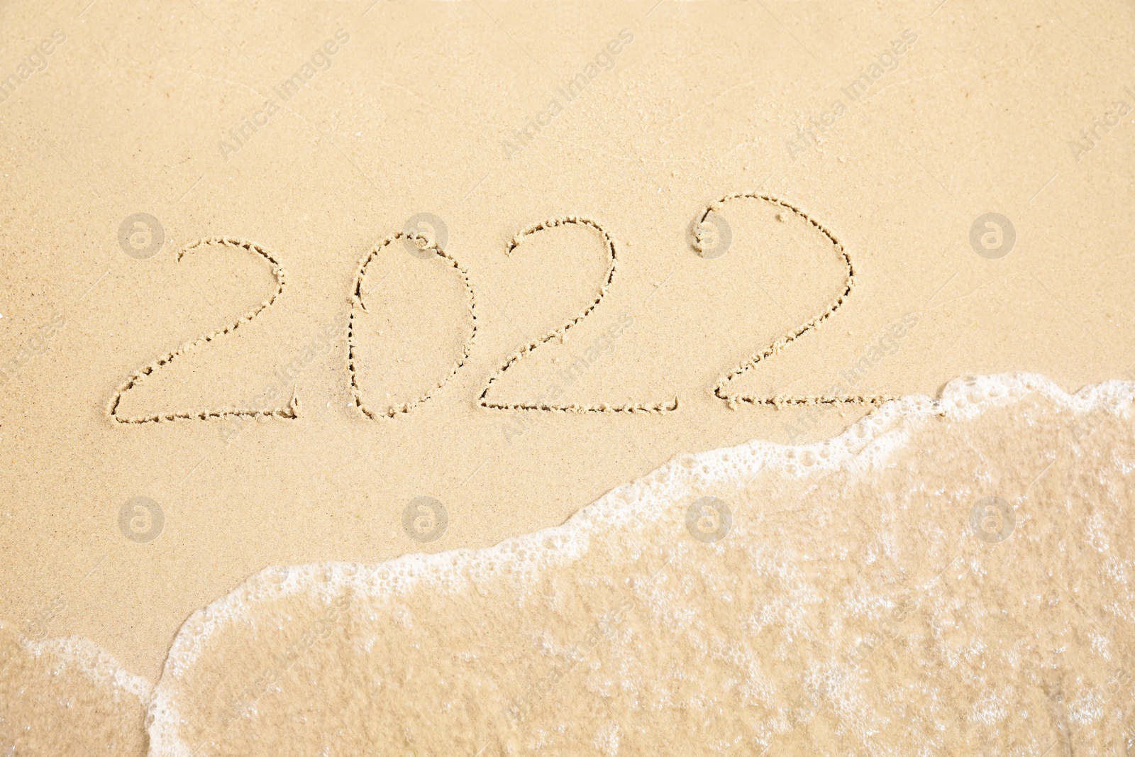 Photo of Sandy beach with written 2022 washed by sea. Happy New Year, above view