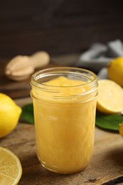 Photo of Delicious lemon curd in glass jar on wooden table