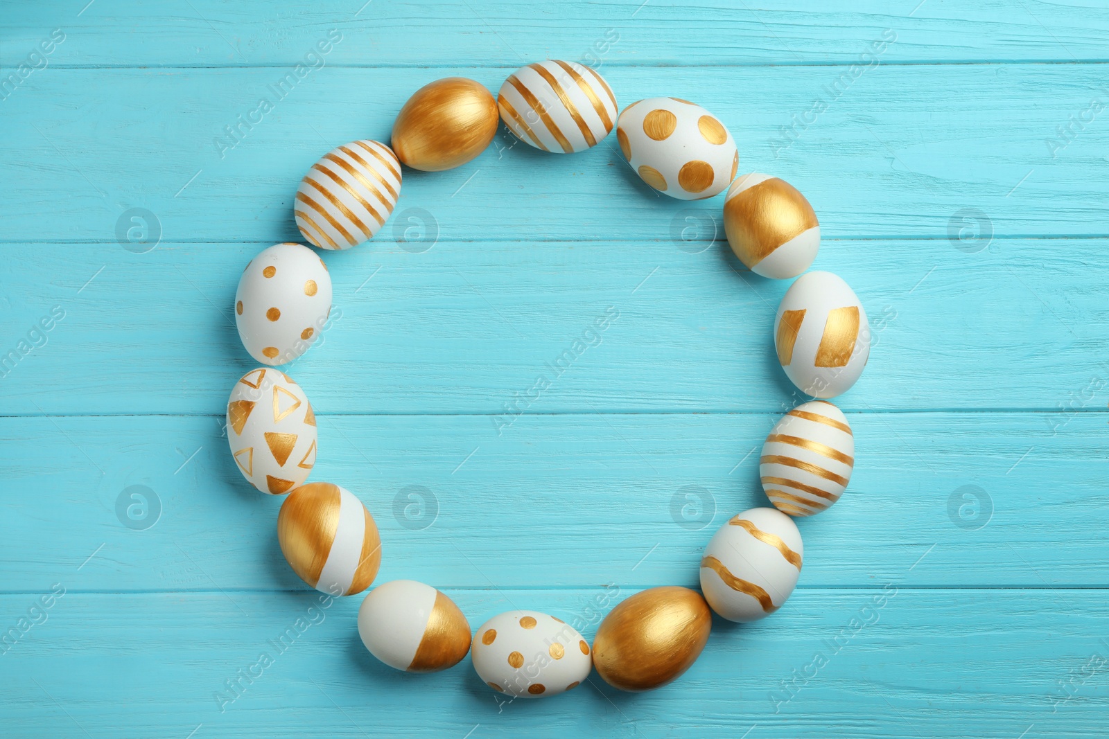 Photo of Frame made of traditional Easter eggs decorated with golden paint on wooden background, top view. Space for text