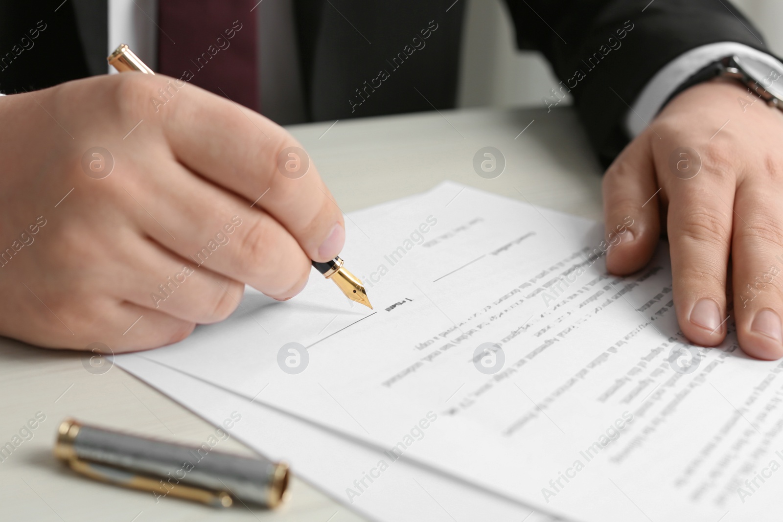 Photo of Notary signing document at wooden table, closeup