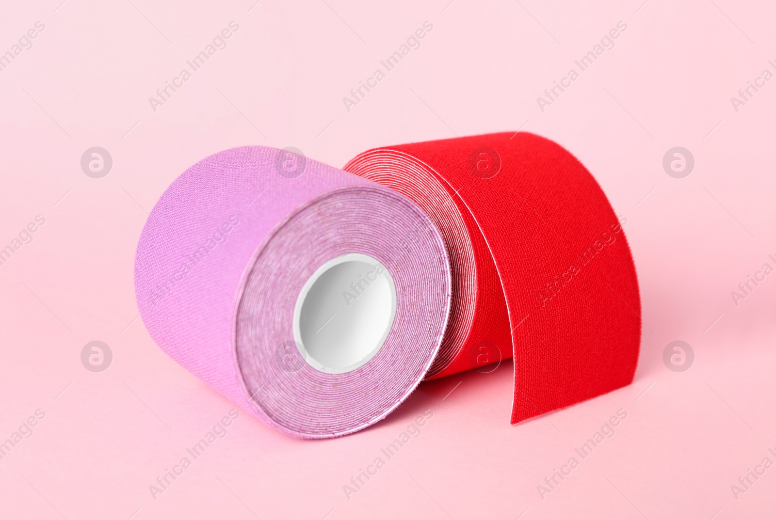 Photo of Bright kinesio tape in rolls on pink background