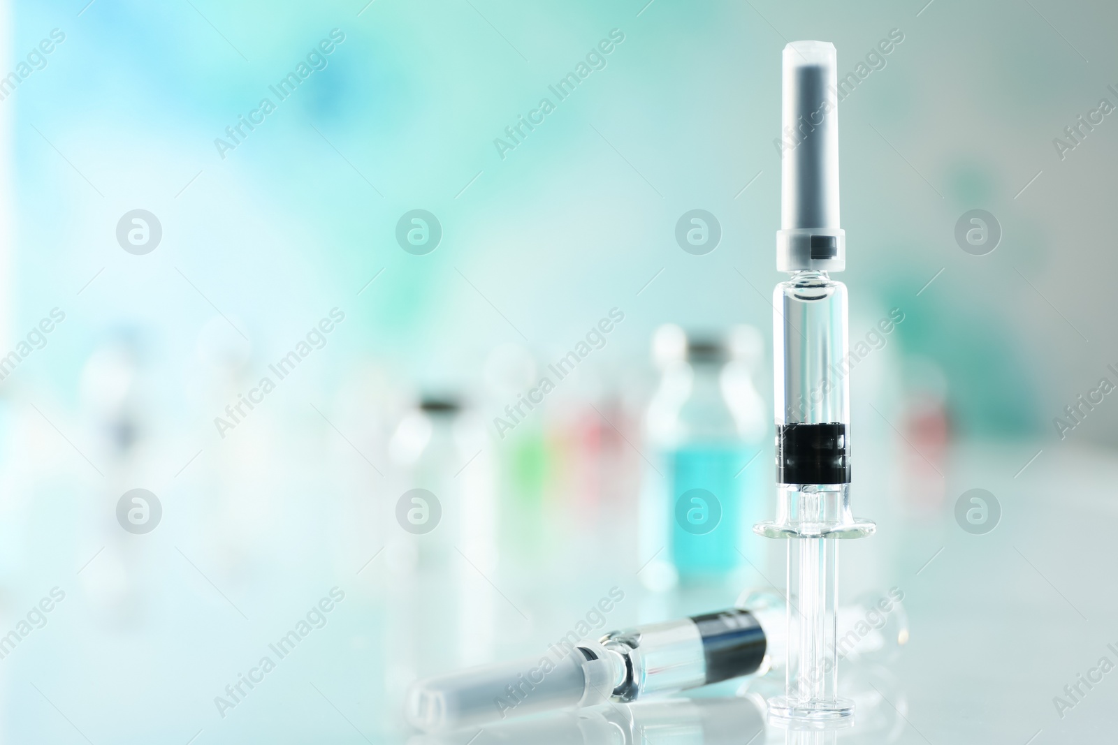 Photo of Syringes with COVID-19 vaccine on white table, space for text