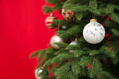 Beautifully decorated Christmas tree against color background, closeup