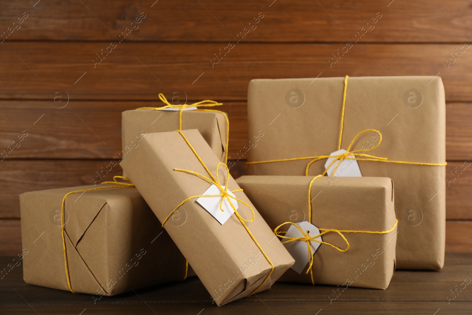 Photo of Parcels wrapped in kraft paper with tags on wooden table