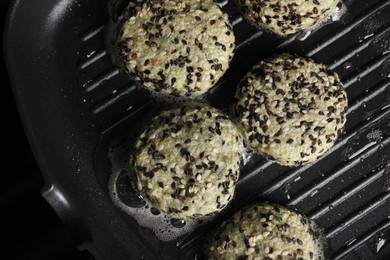 Photo of Cooking tasty vegan cutlets with sesame in grill pan, top view