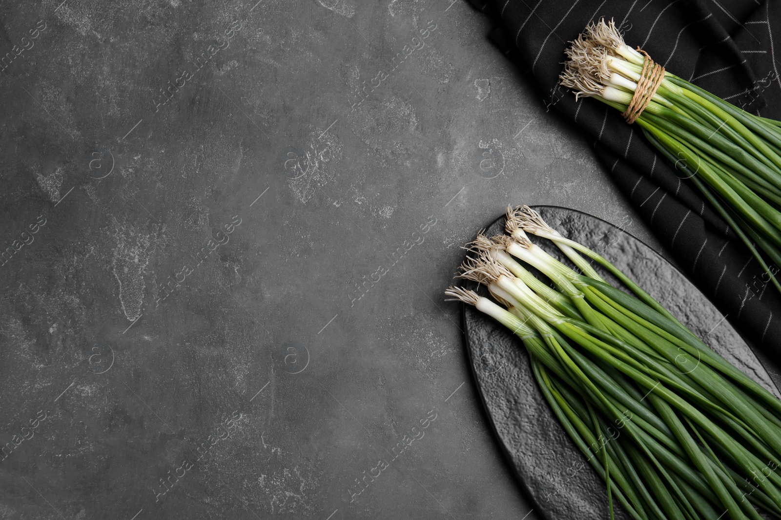 Photo of Fresh green spring onions on grey table, flat lay. Space for text