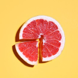 Photo of Cut fresh grapefruit on yellow background, flat lay