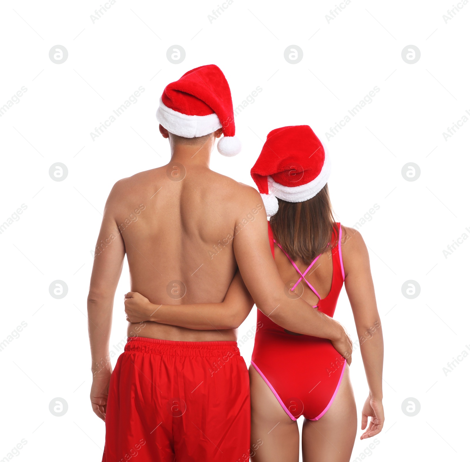 Photo of Lovely couple with Santa hats together on white background, back view. Christmas vacation