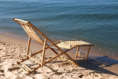 Sandy beach with empty wooden sunbed on sunny day