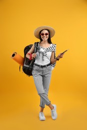 Photo of Happy female tourist with passport, ticket and backpack on yellow background