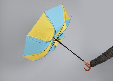 Photo of Man holding umbrella caught in gust of wind on grey background, closeup
