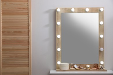 Stylish dressing table with cosmetics, mirror and accessories near white wall