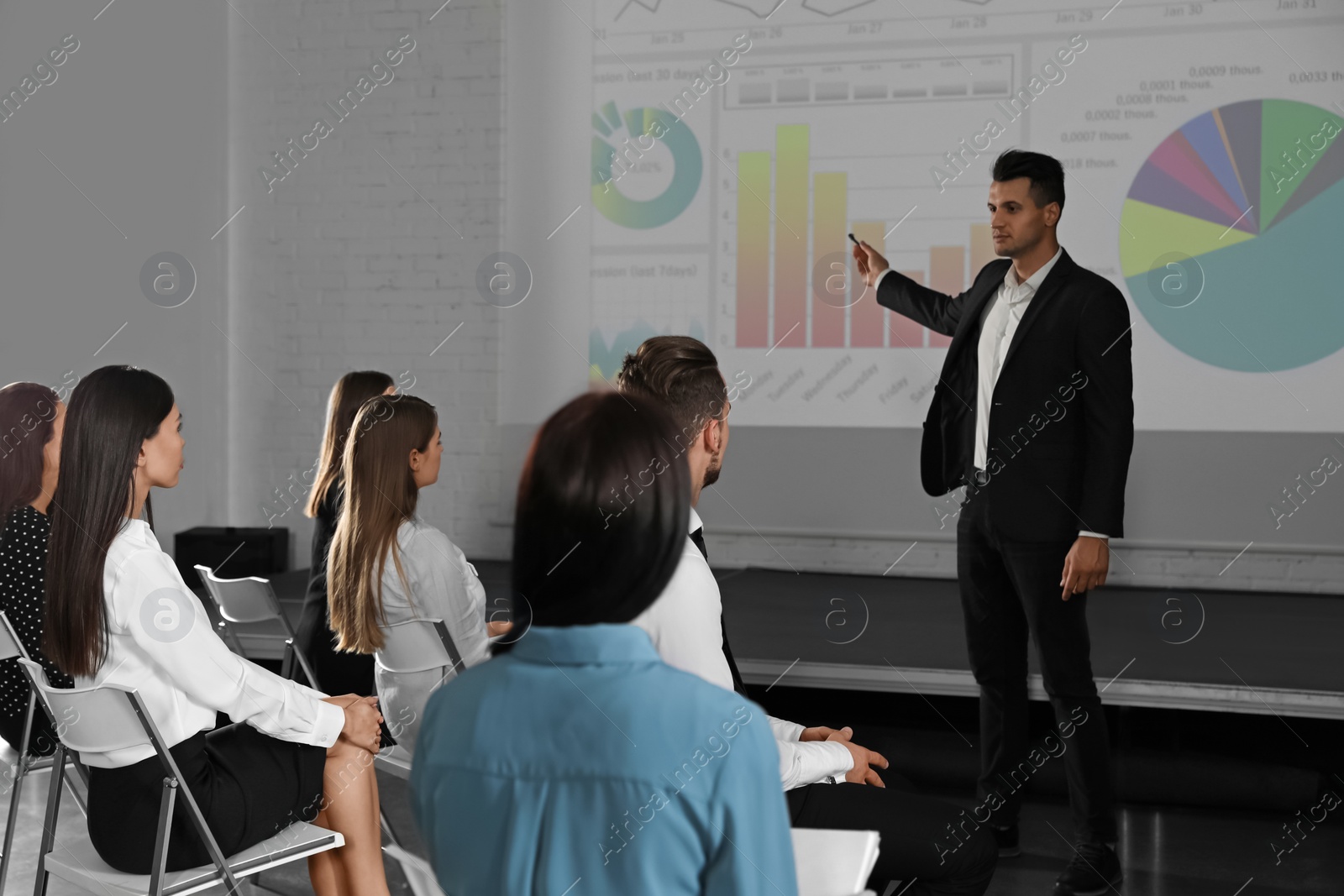 Photo of Male business trainer giving lecture in conference room with projection screen