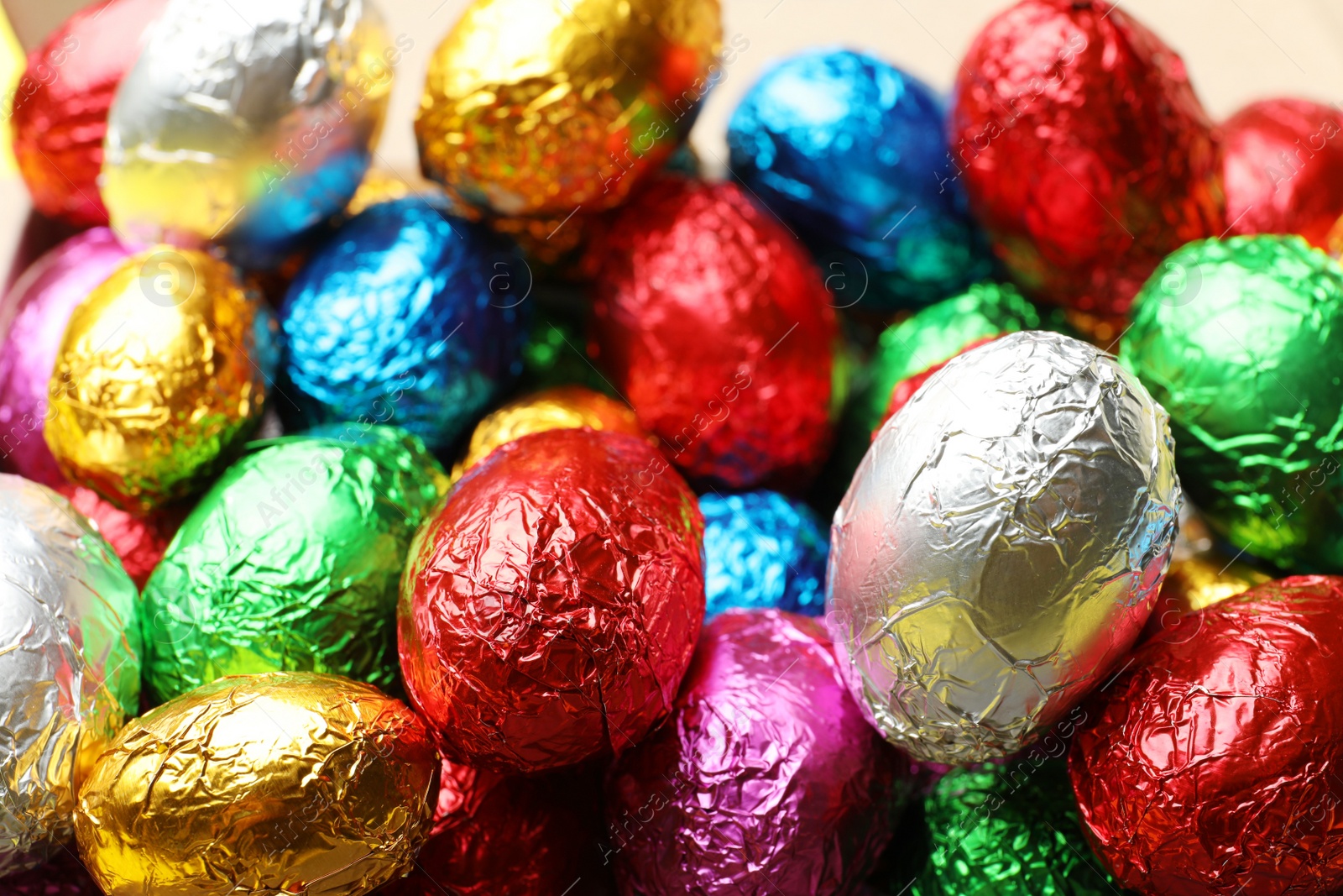 Photo of Chocolate eggs wrapped in colorful foil as background, closeup