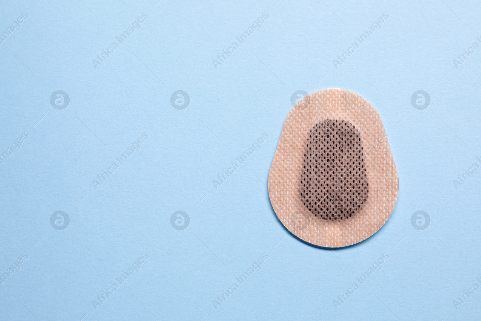 Photo of Contraceptive patch on light blue background, top view. Space for text