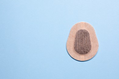 Contraceptive patch on light blue background, top view. Space for text