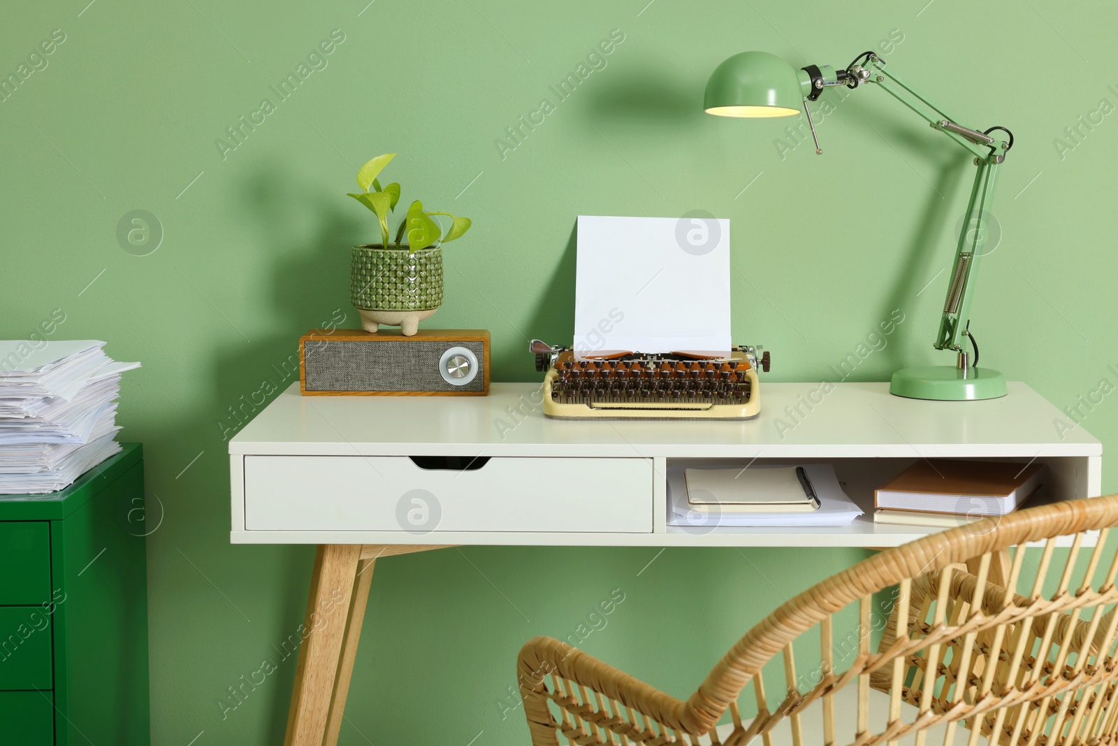 Photo of Writer's workplace with typewriter on wooden desk near pale green wall in room