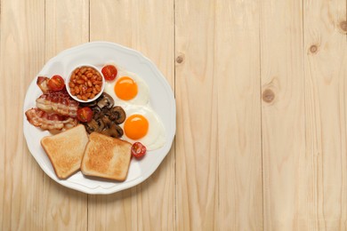 Photo of Plate of fried eggs, mushrooms, beans, bacon, tomatoes and toasts on wooden table, top view with space for text. Traditional English breakfast