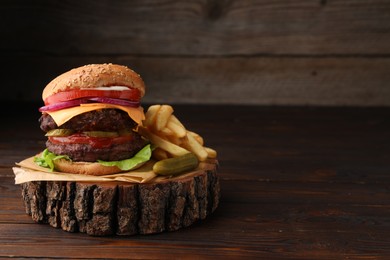Photo of Tasty cheeseburger with patties, French fries and pickle on wooden table. Space for text