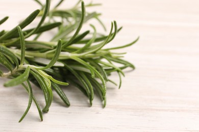 Photo of Fresh green rosemary on white wooden table, closeup. Space for text