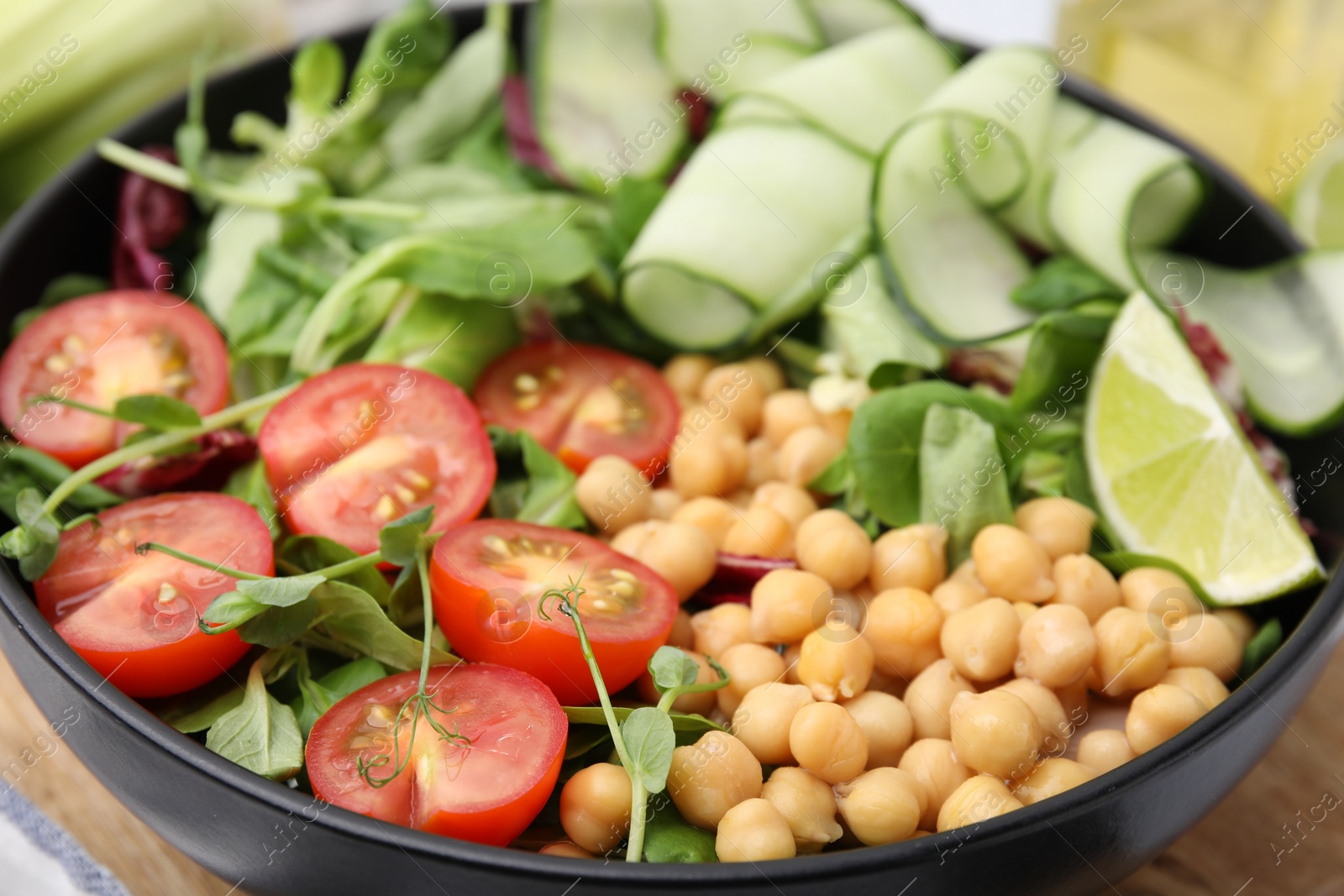 Photo of Tasty salad with chickpeas, cherry tomatoes and cucumbers in bowl, closeup