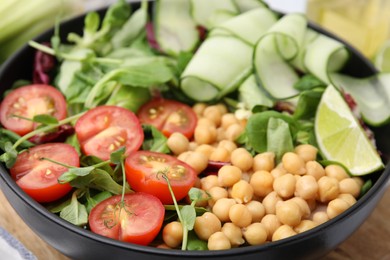 Photo of Tasty salad with chickpeas, cherry tomatoes and cucumbers in bowl, closeup