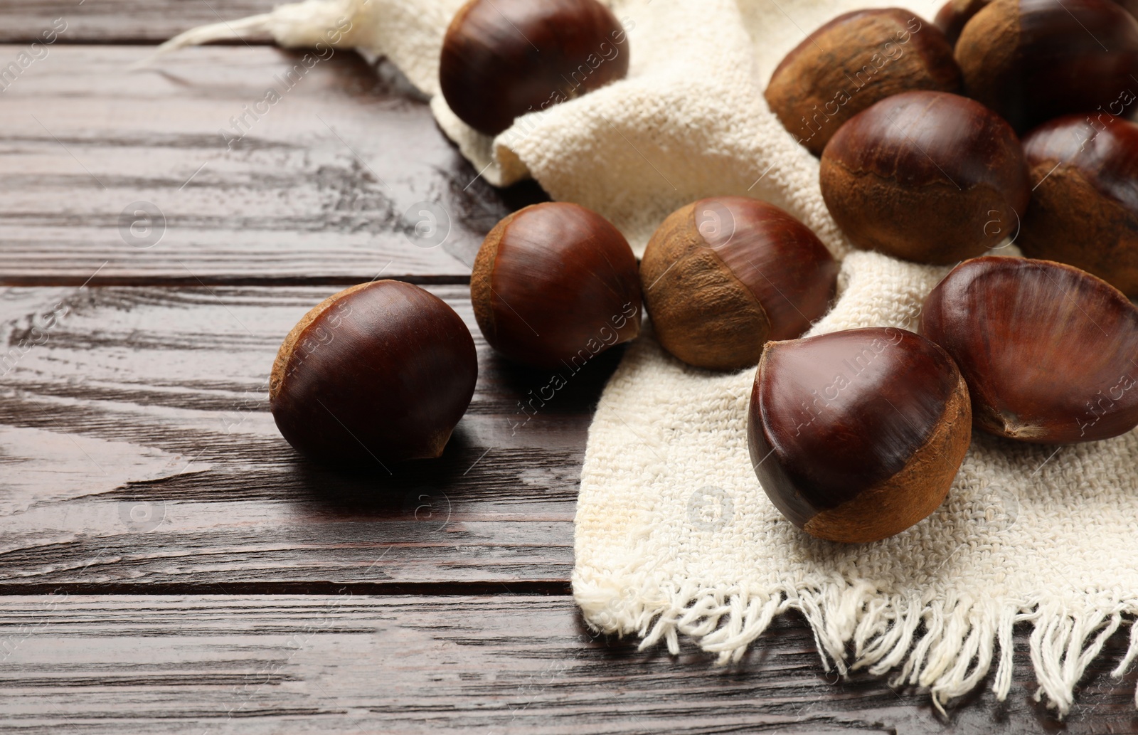 Photo of Sweet fresh edible chestnuts on wooden table, closeup