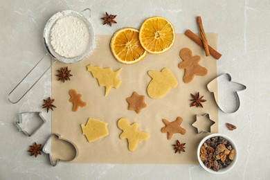 Photo of Flat lay composition with unbaked cookies and cutters on light grey table. Christmas biscuits