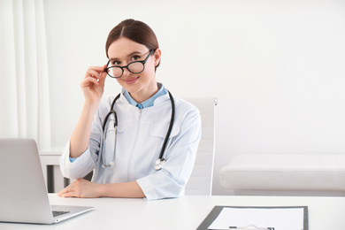 Portrait of young female doctor in white coat at workplace
