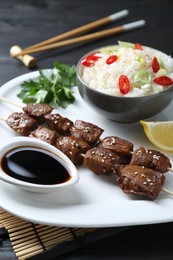 Photo of Tasty chicken meat glazed in soy sauce served with rice on black table, closeup