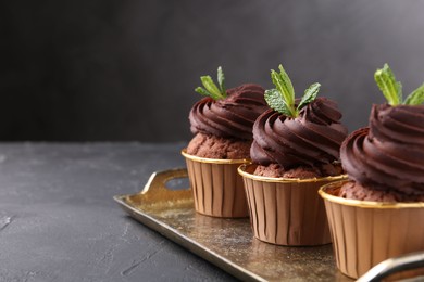 Photo of Delicious chocolate cupcakes with mint on black textured table. Space for text