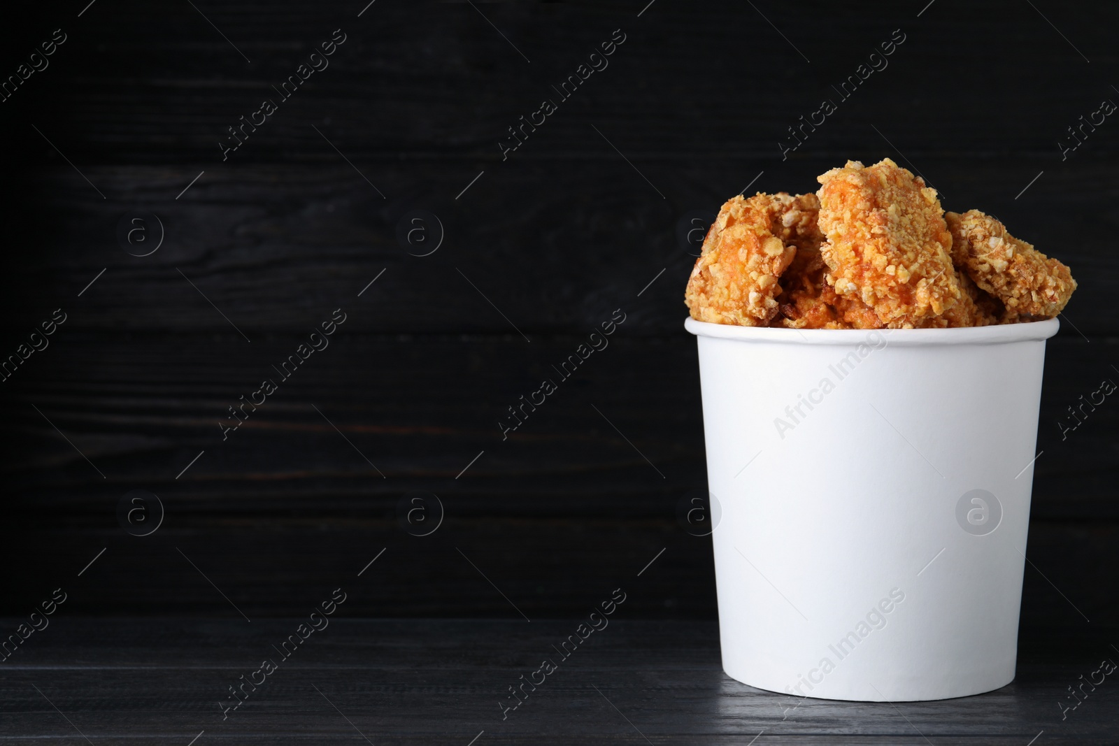 Photo of Bucket with yummy nuggets on wooden table, space for text