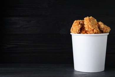 Bucket with yummy nuggets on wooden table, space for text