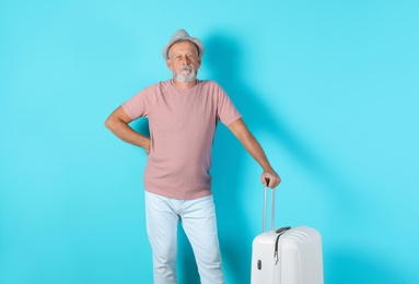 Photo of Senior man with suitcase on color background. Vacation travel
