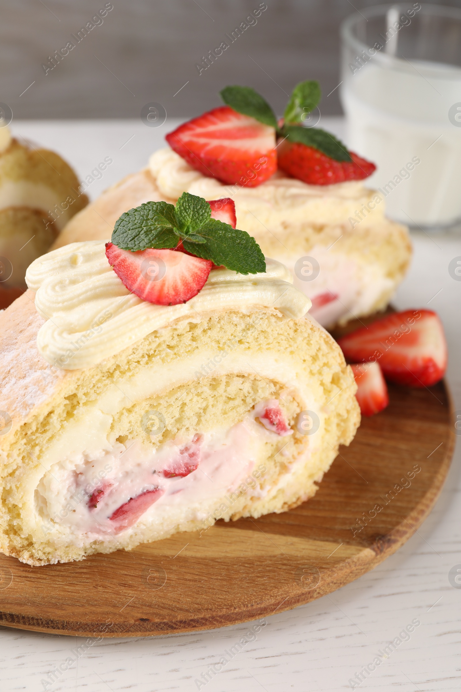 Photo of Delicious cake roll with strawberries and cream on wooden board, closeup