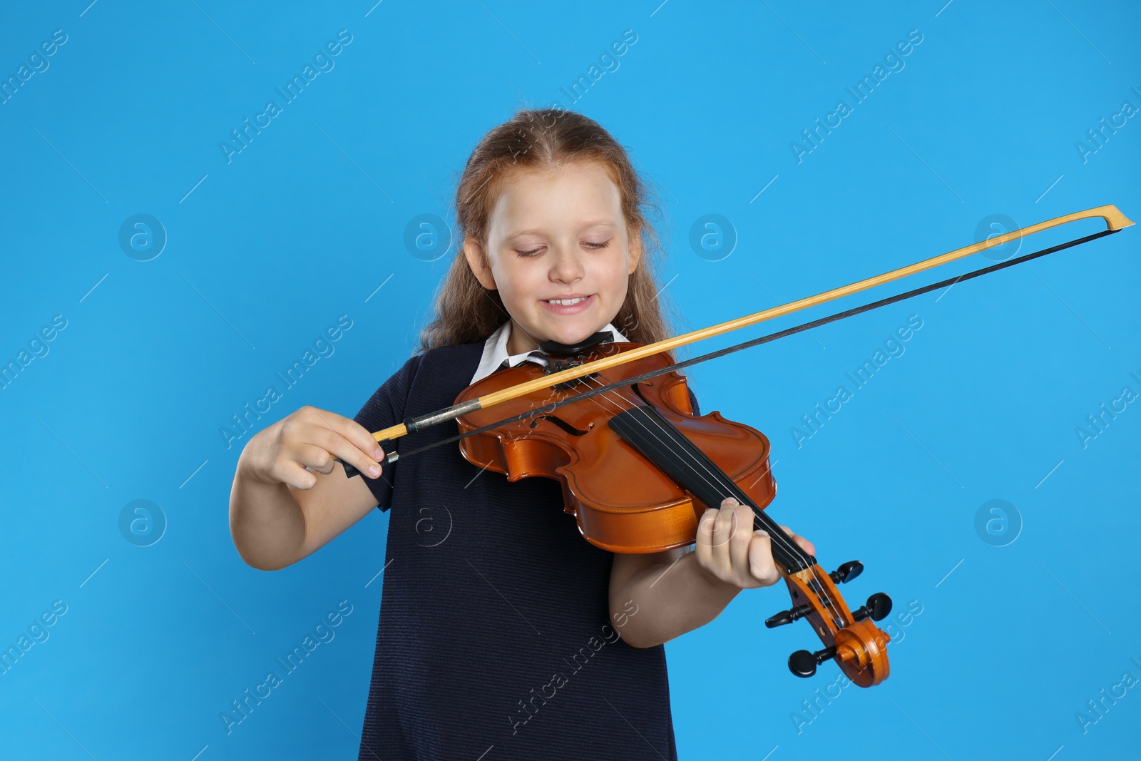 Photo of Preteen girl playing violin on light blue background