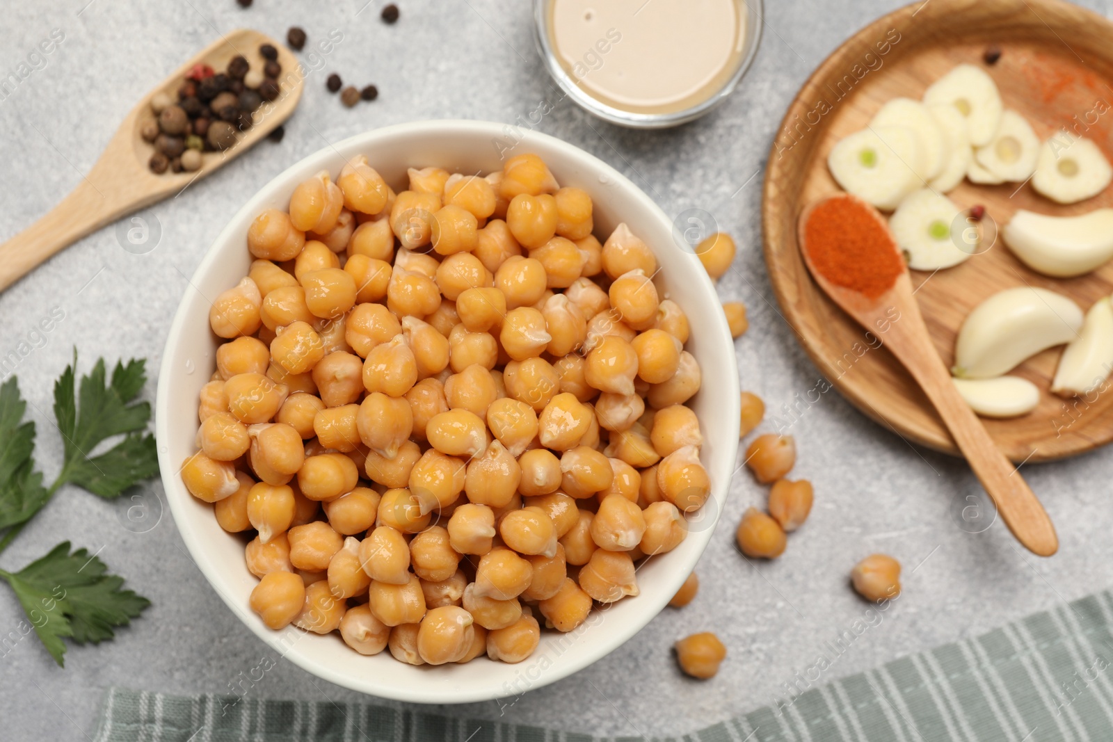 Photo of Delicious chickpeas and different ingredients on light grey table, flat lay. Cooking hummus