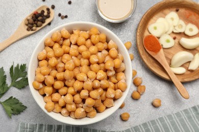 Photo of Delicious chickpeas and different ingredients on light grey table, flat lay. Cooking hummus