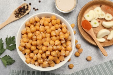 Delicious chickpeas and different ingredients on light grey table, flat lay. Cooking hummus